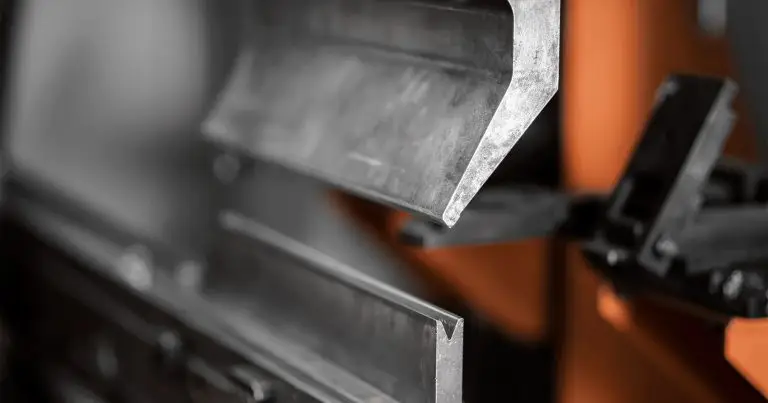 Close-up of a metal bending machine in operation, with a sheet of metal being precisely formed into an angular shape