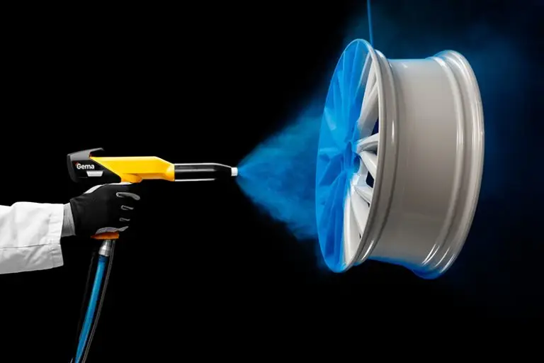 Technician applying blue powder coating to a metallic wheel rim using a spray gun
